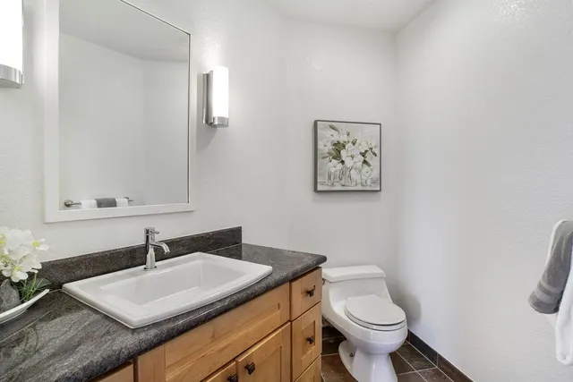 a bathroom with a granite countertop sink and a toilet