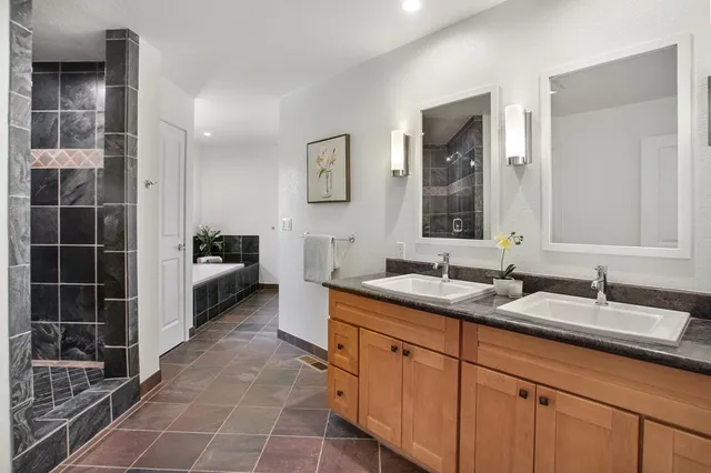 a spacious bathroom with a granite countertop sink a mirror and a shower