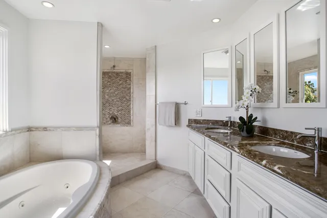 a bathroom with a granite countertop tub sink and mirror