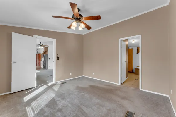 a view of a big room with wooden floor and chandelier fan