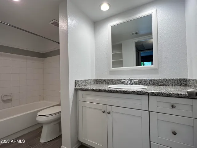 a bathroom with a granite countertop toilet sink and mirror