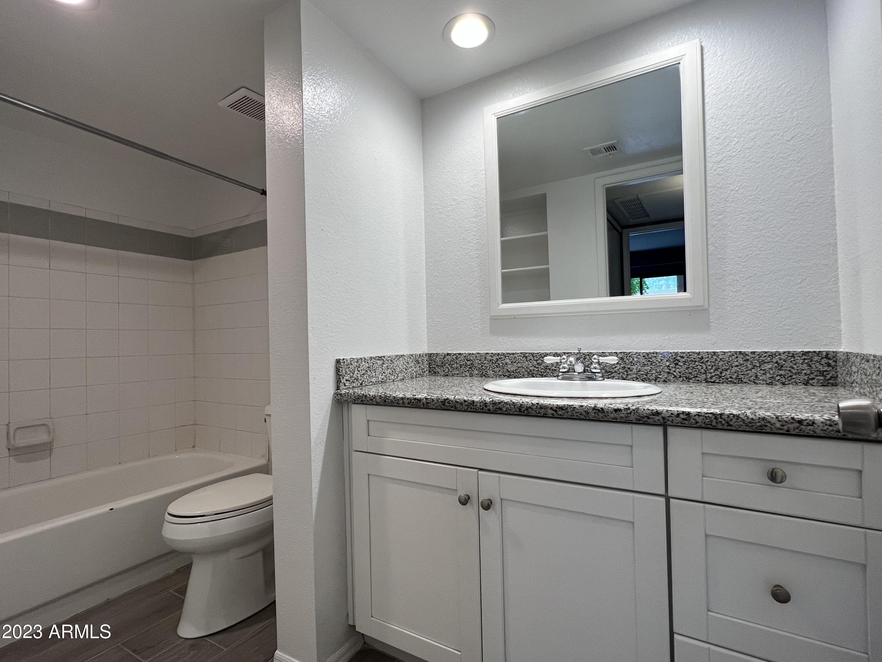 4850 East Desert Cove Avenue, Unit 105 Scottsdale, AZ 85254 - Photo 6 of 12 a bathroom with a granite countertop toilet sink and mirror