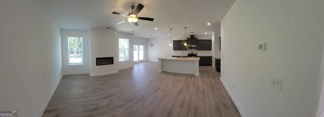 a living room with stainless steel appliances furniture a fireplace and a ceiling fan