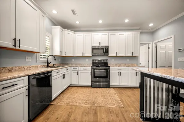 a kitchen with kitchen island granite countertop a sink cabinets stainless steel appliances and a counter top space