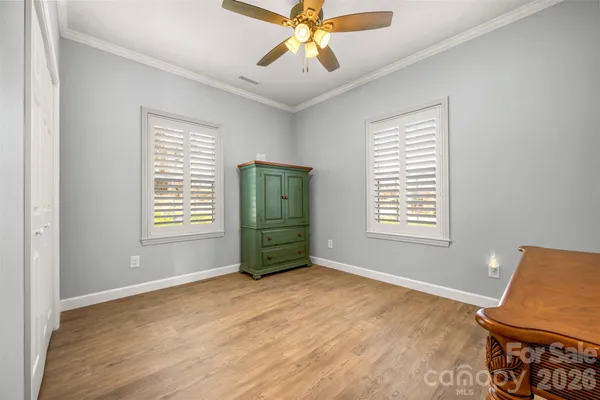 a view of an empty room with window and kitchen view