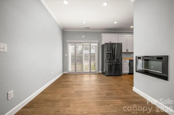 a view of a electric appliances in kitchen and empty room with wooden floor