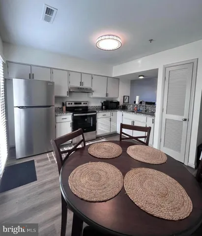 a kitchen with sink refrigerator dining table and chairs