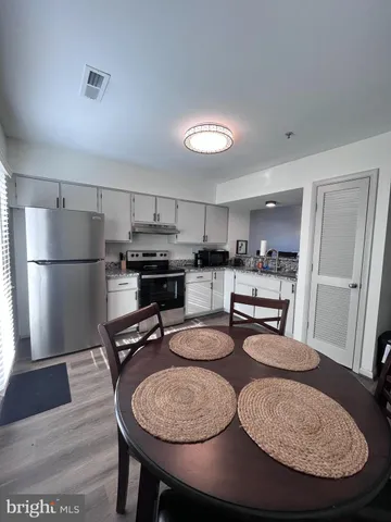 a room with stainless steel appliances granite countertop a dining table chairs and refrigerator