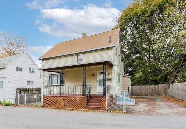 a view of a white house with large windows and wooden fence