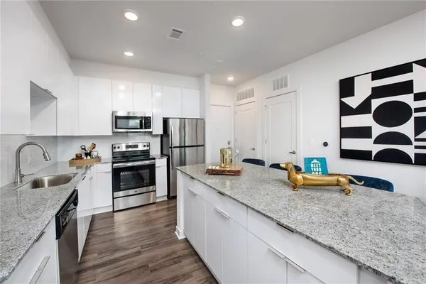 a kitchen with stainless steel appliances granite countertop a table chairs sink and cabinets