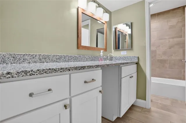 a bathroom with a granite countertop sink a mirror and a shower