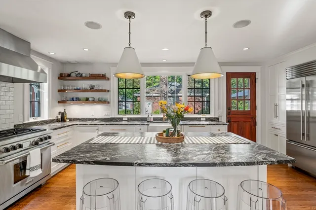 a kitchen with stainless steel appliances granite countertop a sink a stove and a wooden floors