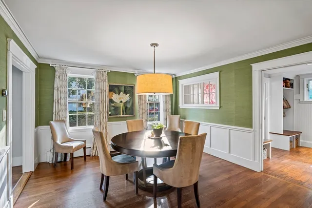 a dining room with furniture wooden floor a rug a potted plant and a chandelier