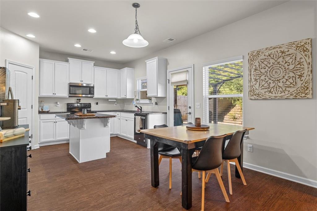 329 Rippling Drive Ball Ground, GA 30107 - Photo 11 of 43 a kitchen with stainless steel appliances granite countertop a stove a sink a microwave a dining table and chairs