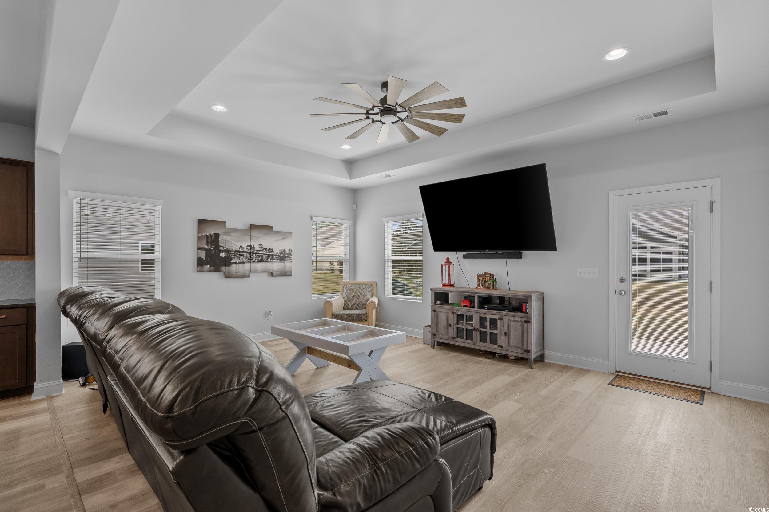 2064 Hazlette Loop Conway, SC 29526 - Photo 12 of 39 Living room featuring a tray ceiling, baseboards, light wood-style floors, visible vents, and a ceiling fan