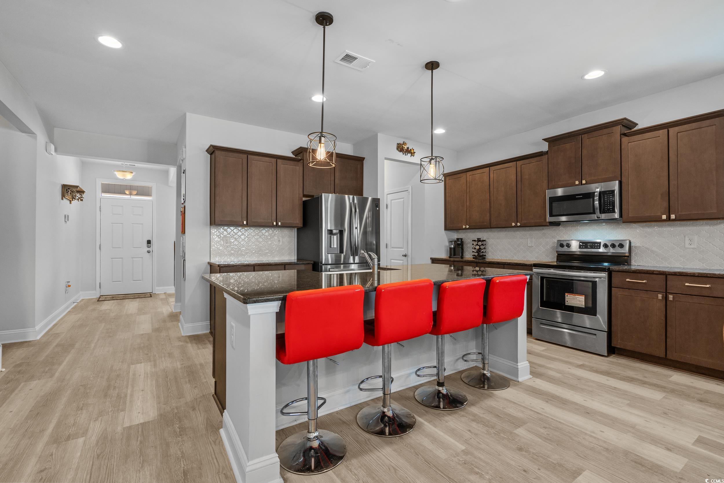 2064 Hazlette Loop Conway, SC 29526 - Photo 18 of 39 Kitchen with a kitchen bar, stainless steel appliances, an island with sink, light wood-style floors, and visible vents