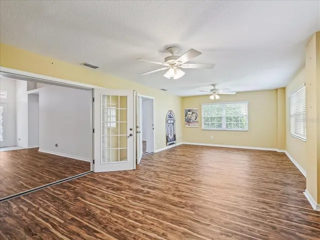 a view of an empty room with a window and a kitchen