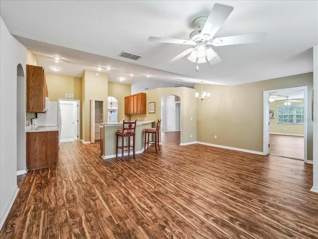 a view of a kitchen with kitchen island stainless steel appliances wooden floor and a view of living room