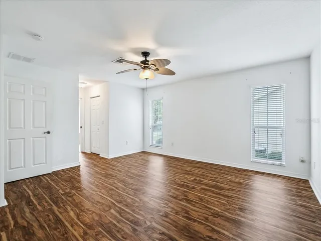 a view of an empty room with wooden floor and a window