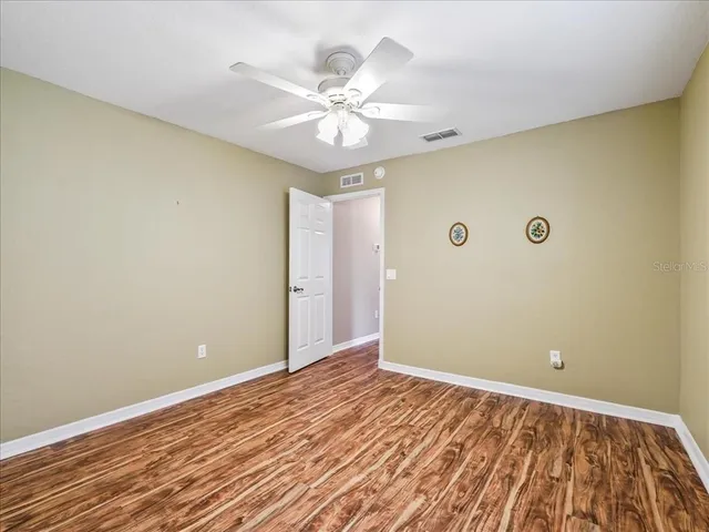 a view of a room with wooden floor and a ceiling fan