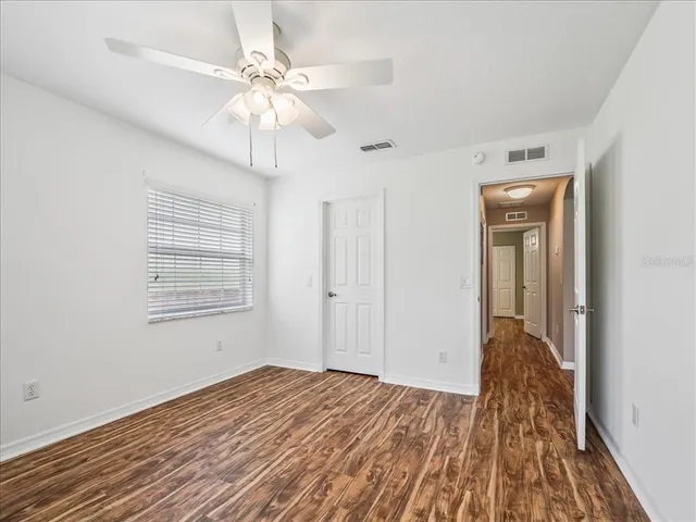 a view of a livingroom with a chandelier fan and wooden floor