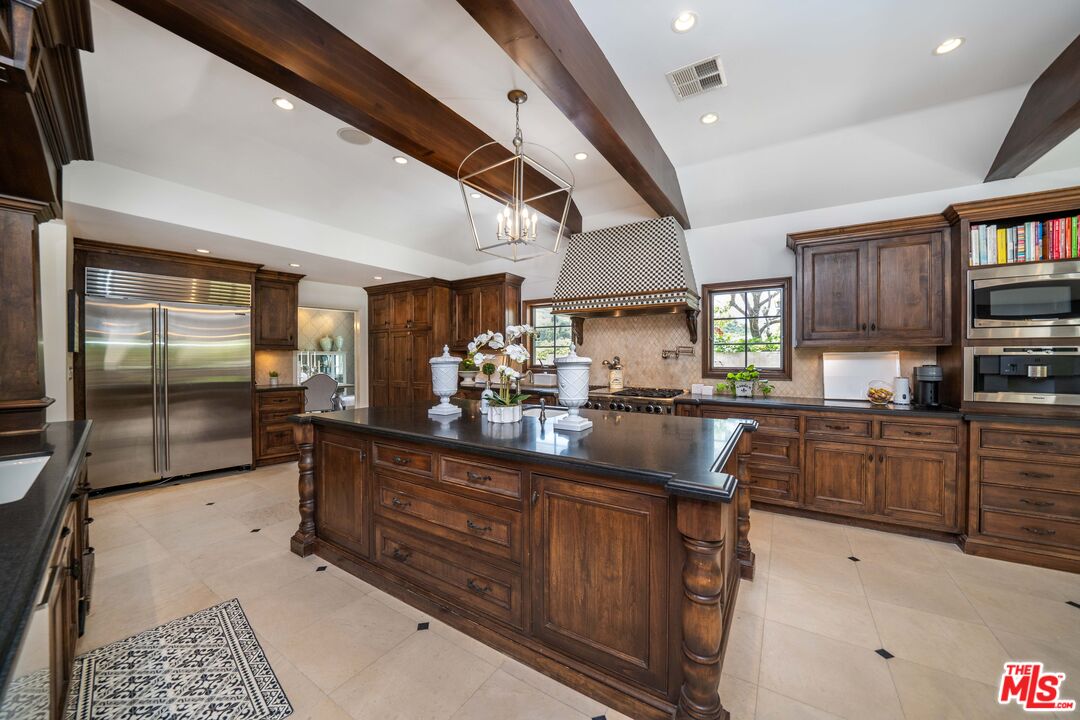 16632 Bienveneda Place Pacific Palisades, CA 90272 - Photo 16 of 62 a kitchen with stainless steel appliances kitchen island granite countertop a refrigerator a sink dishwasher a stove and a dining table with wooden floor
