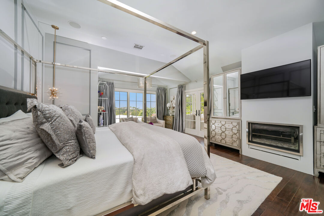16632 Bienveneda Place Pacific Palisades, CA 90272 - Photo 27 of 62 a spacious bedroom with a bed a flat screen tv and a fireplace