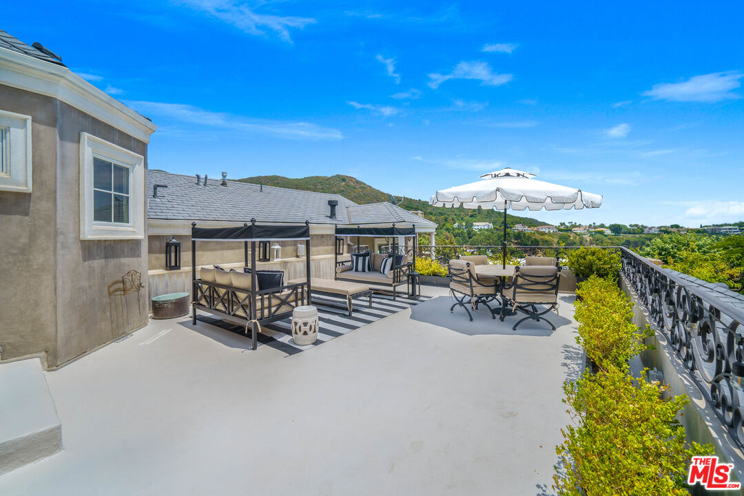 16632 Bienveneda Place Pacific Palisades, CA 90272 - Photo 37 of 62 a view of a patio with a table and chairs under an umbrella with wooden fence