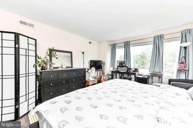 a large bedroom with a bed a large window and dresser