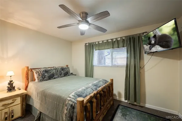 a bedroom with a large bed and a flat tv screen on dresser