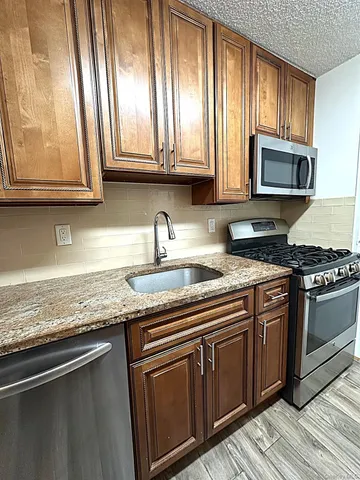 a kitchen with stainless steel appliances granite countertop a sink a stove and microwave