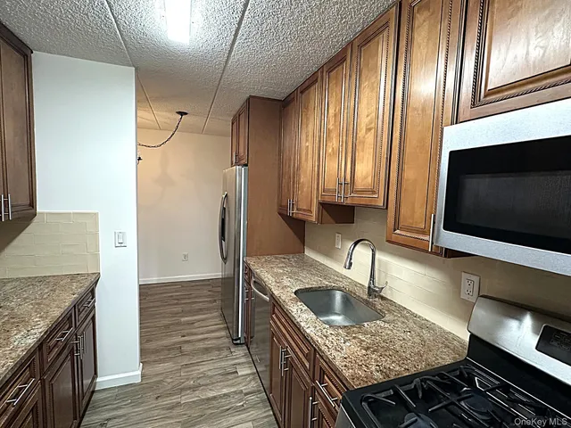 a kitchen with granite countertop stainless steel appliances a sink stove and refrigerator