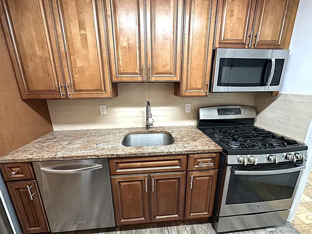 a kitchen with granite countertop a stove top oven cabinetry a sink and a window