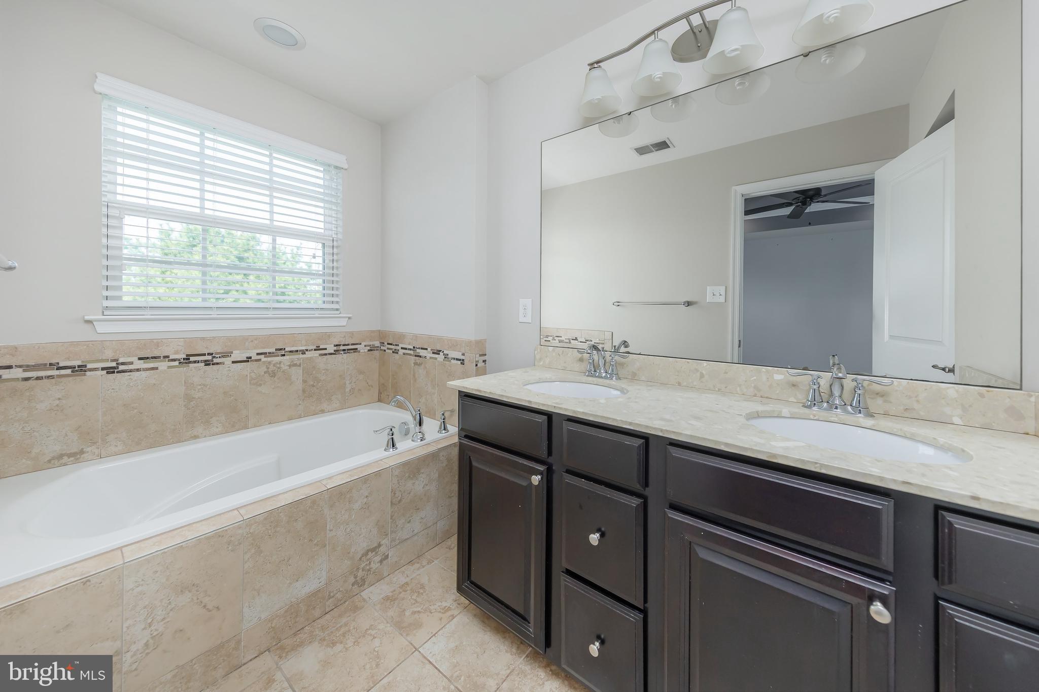 1036 Regency Place Sewell, NJ 08080 - Photo 16 of 18 a bathroom with a granite countertop bathtub a sink and a window