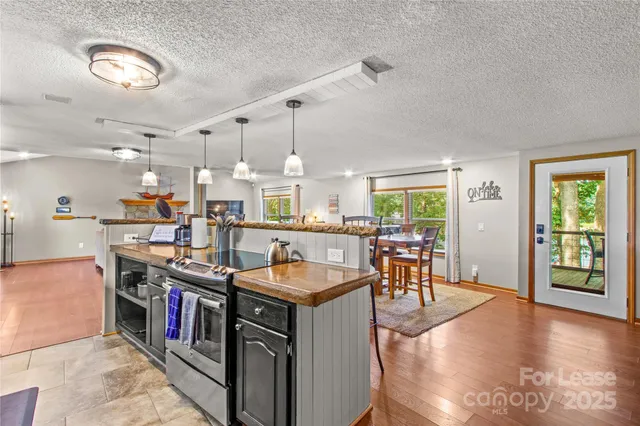 a open kitchen with stainless steel appliances granite countertop a stove oven a dining table and chairs with wooden floor
