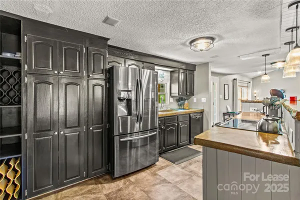 a kitchen with granite countertop a refrigerator and stainless steel appliances
