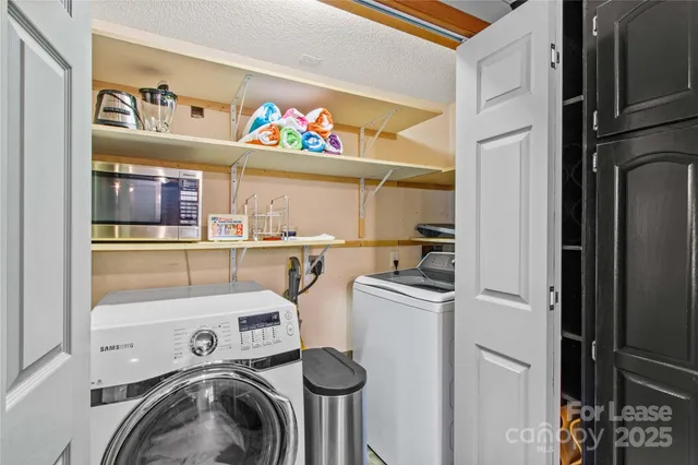 a utility room with dryer washer and a view of living room