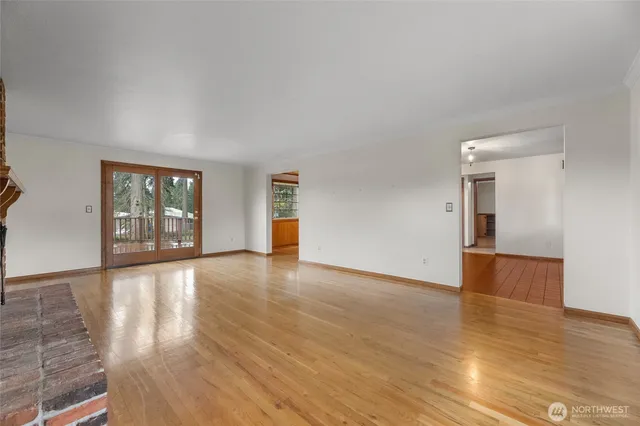 a view of an empty room with window and wooden floor