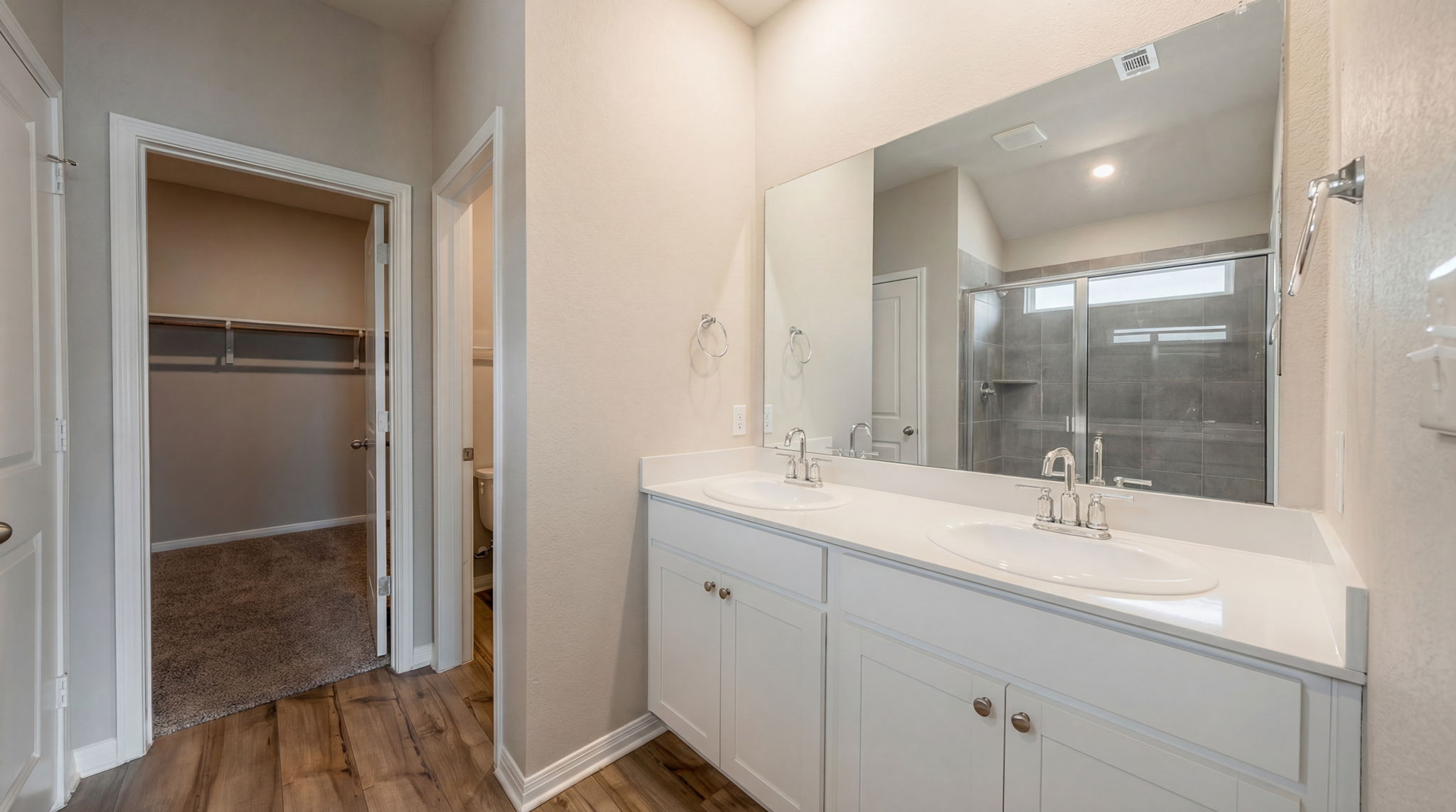 1003 Round Bale Road Hutto, TX 78634 - Photo 7 of 29 Full bath with double vanity, a spacious closet, dark wood-style flooring, and a stall shower