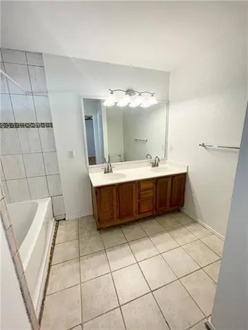 a bathroom with a double vanity sink mirror and bathtub
