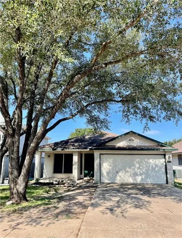 a view of a house with a yard and large tree