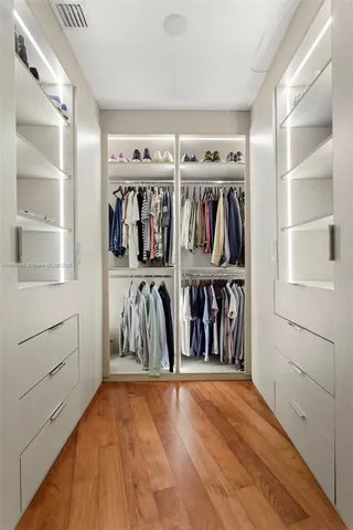 a view of walk in closet with clothes and shoes