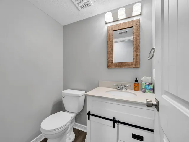 a bathroom with a toilet sink vanity and mirror