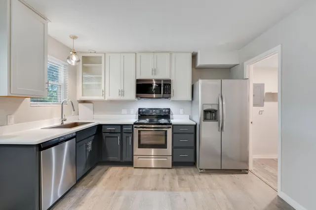 a kitchen with a sink a microwave a refrigerator and cabinets