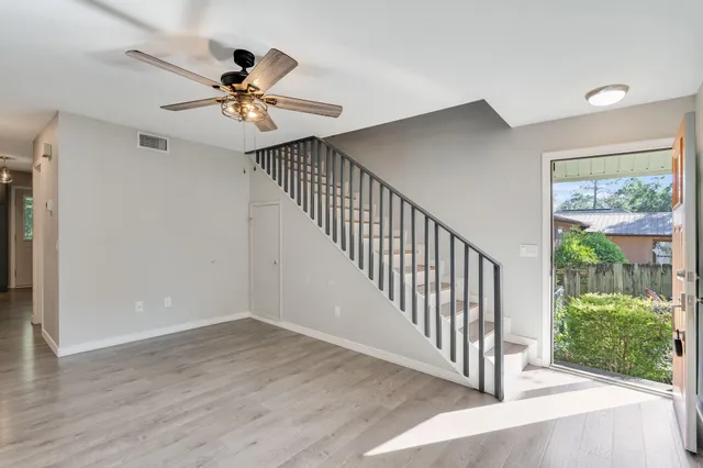 a view of a hallway with wooden floor and a ceiling fan