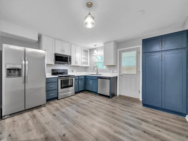 a kitchen with stainless steel appliances a refrigerator a sink cabinets and wooden floor