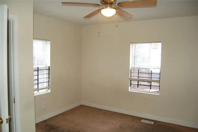 an empty room with windows and chandelier fan