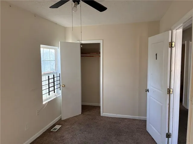 an empty room with windows and ceiling fan