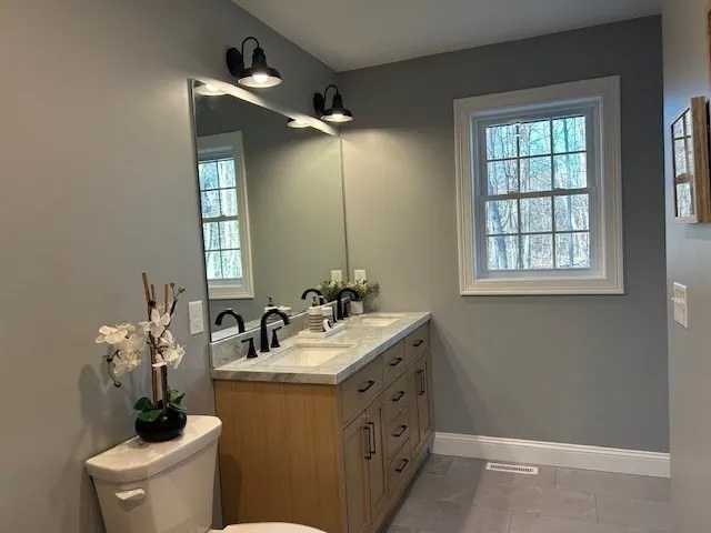 a bathroom with a sink mirror and a toilet