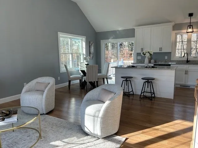 a living room with couches and kitchen view with wooden floor